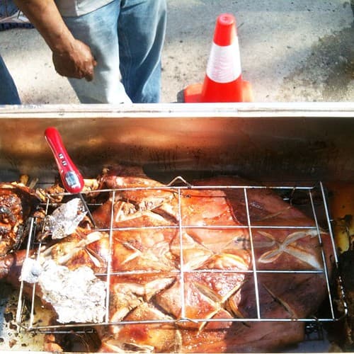 Rejilla con cuyes a medio cocinar y termómetro de cocción